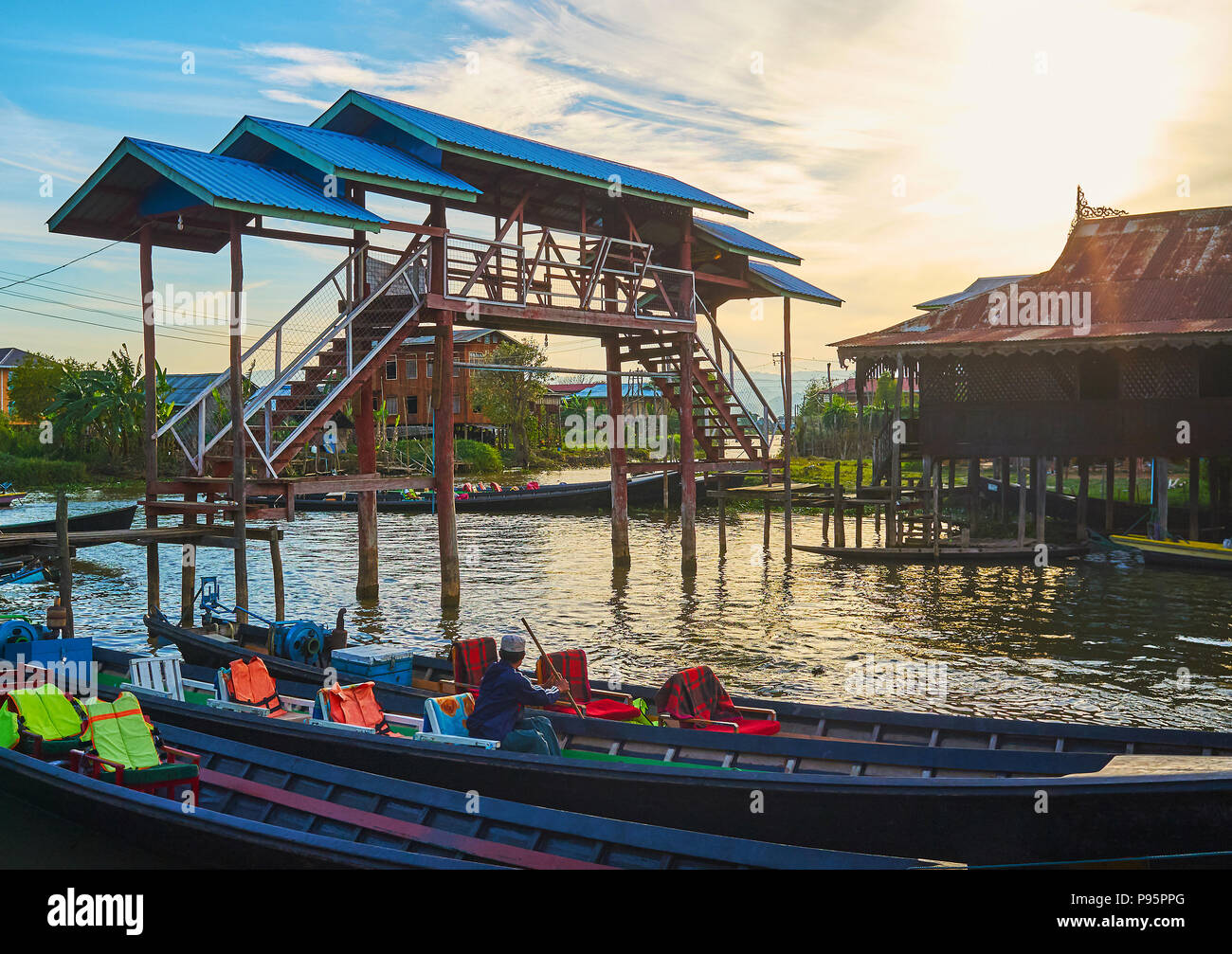 The sunset sky over the old wooden bridge, located next to the wharf of Nga Phe Chaung Monastery of Jumping Cats, Ywama, Inle Lake, Myanmar. Stock Photo