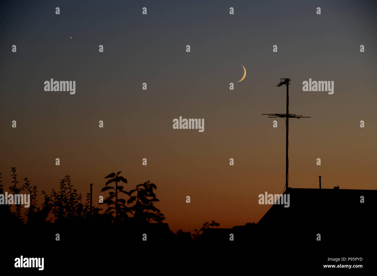 Conjunction between Moon and Venus seen in the evening in urban surroundings. Stock Photo