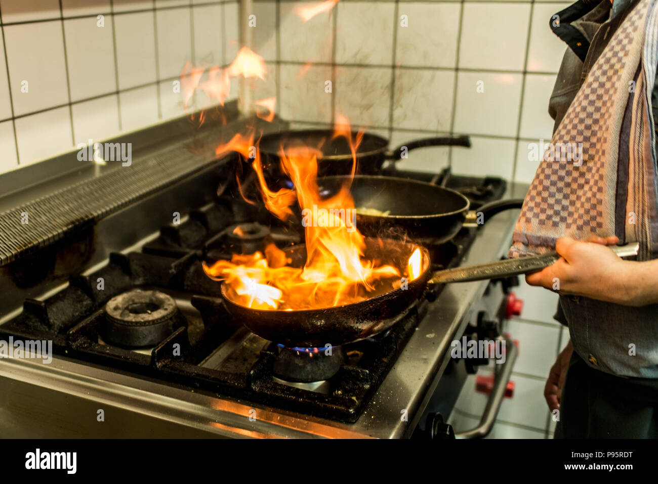 restaurant Chef cooking with flame in a frying pan on a kitchen stove