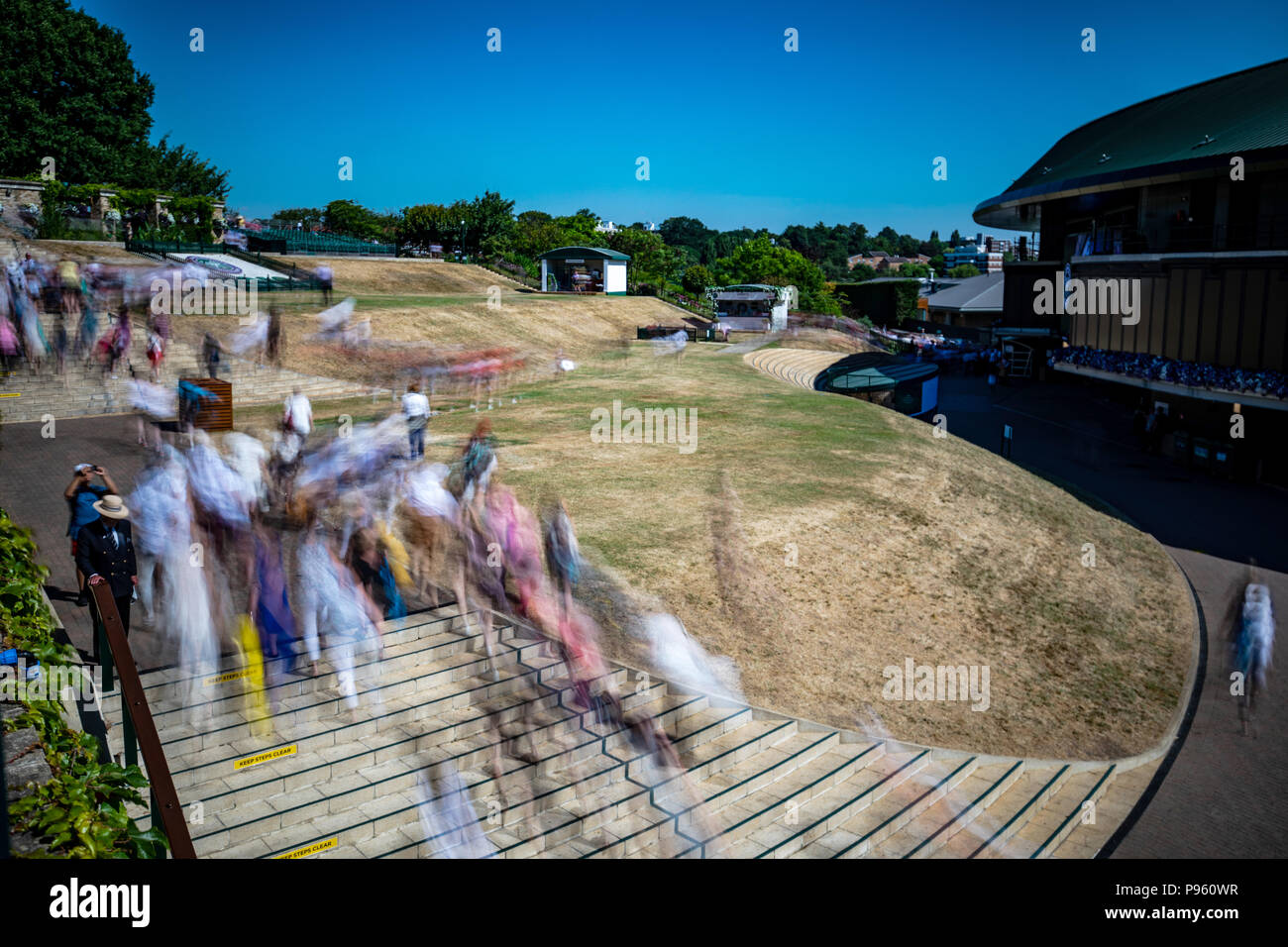 Spectators are led into the grounds at the start of day thirteen of the Wimbledon Championships at the All England Lawn Tennis and Croquet Club, Wimbledon. Stock Photo