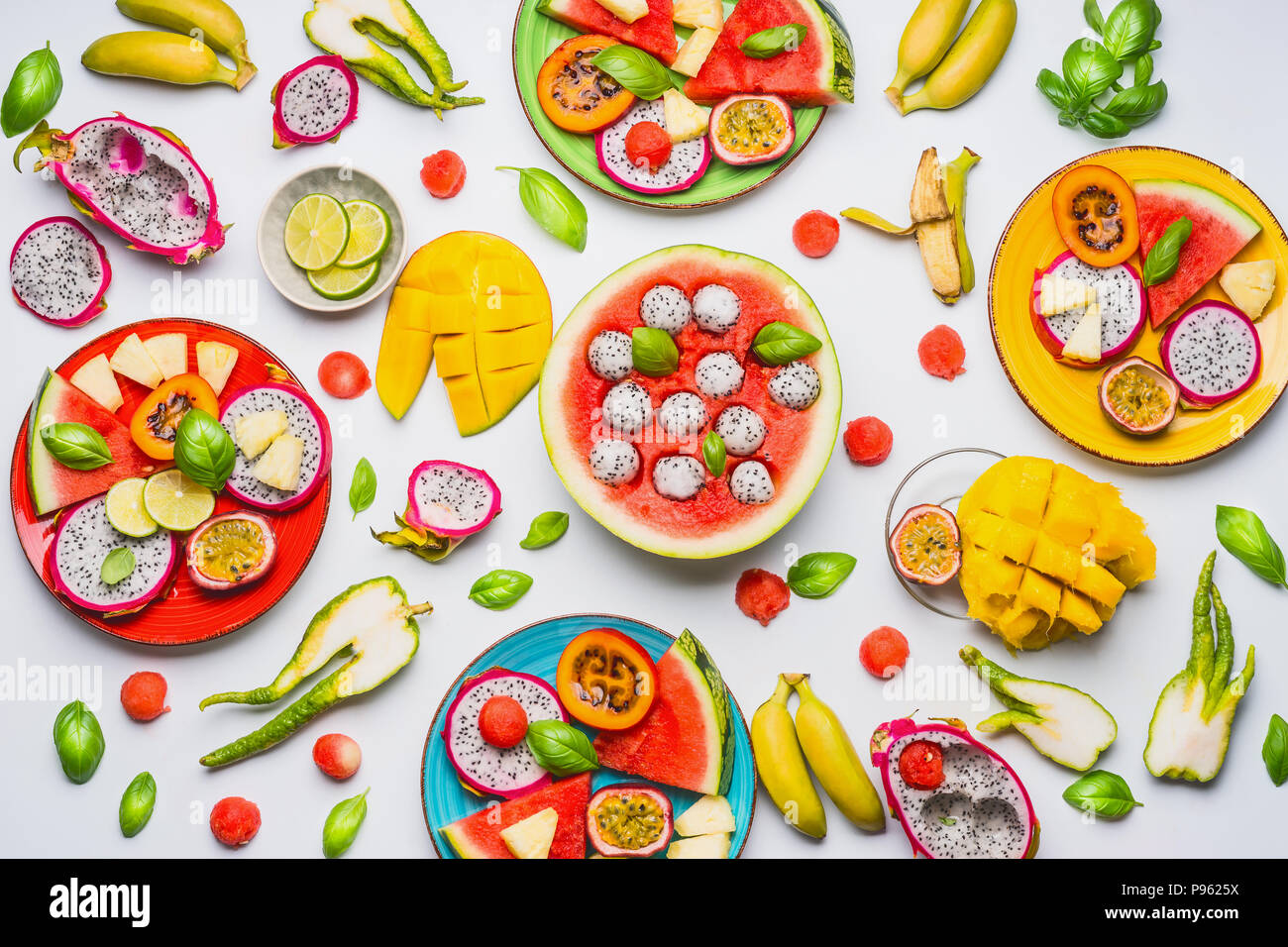 Flat lay of summer various colorful sliced tropical fruits and berries in plates and bowls  on white  background, top view.  Clean and healthy lifesty Stock Photo