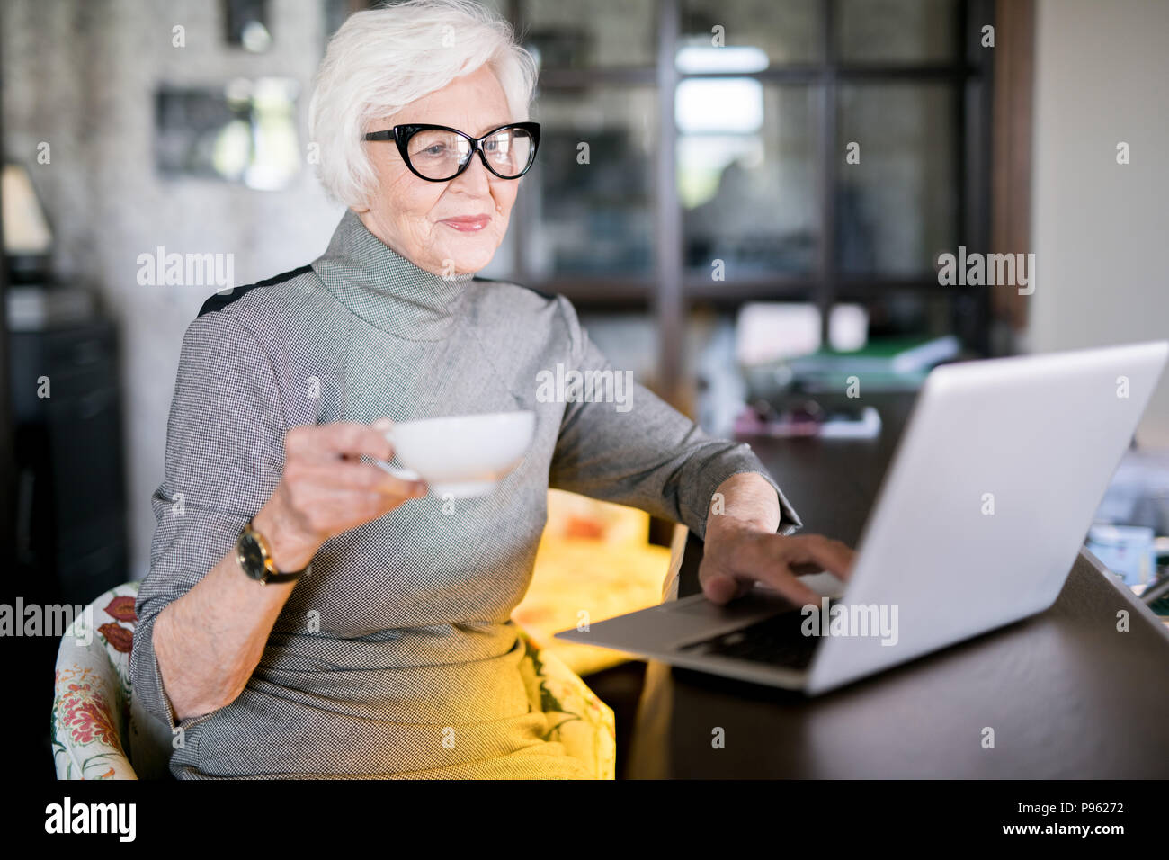 Elderly woman using laptop at cafe Stock Photo