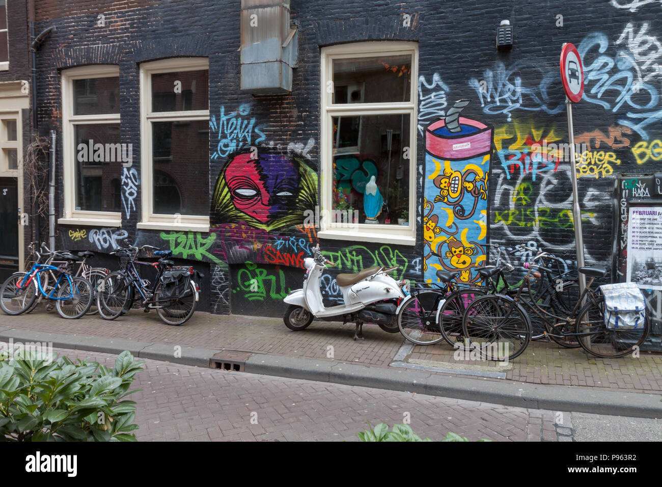 An Amsterdam street scene with graffiti, a scooter, bicycles and the ...