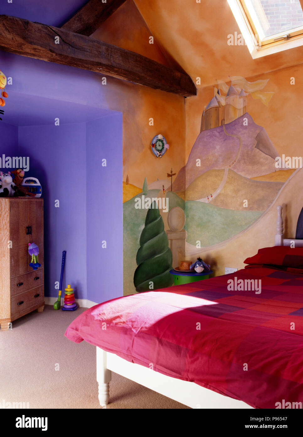 Pink duvet on bed in a children's nineties bedroom with a mural painted on the walls Stock Photo