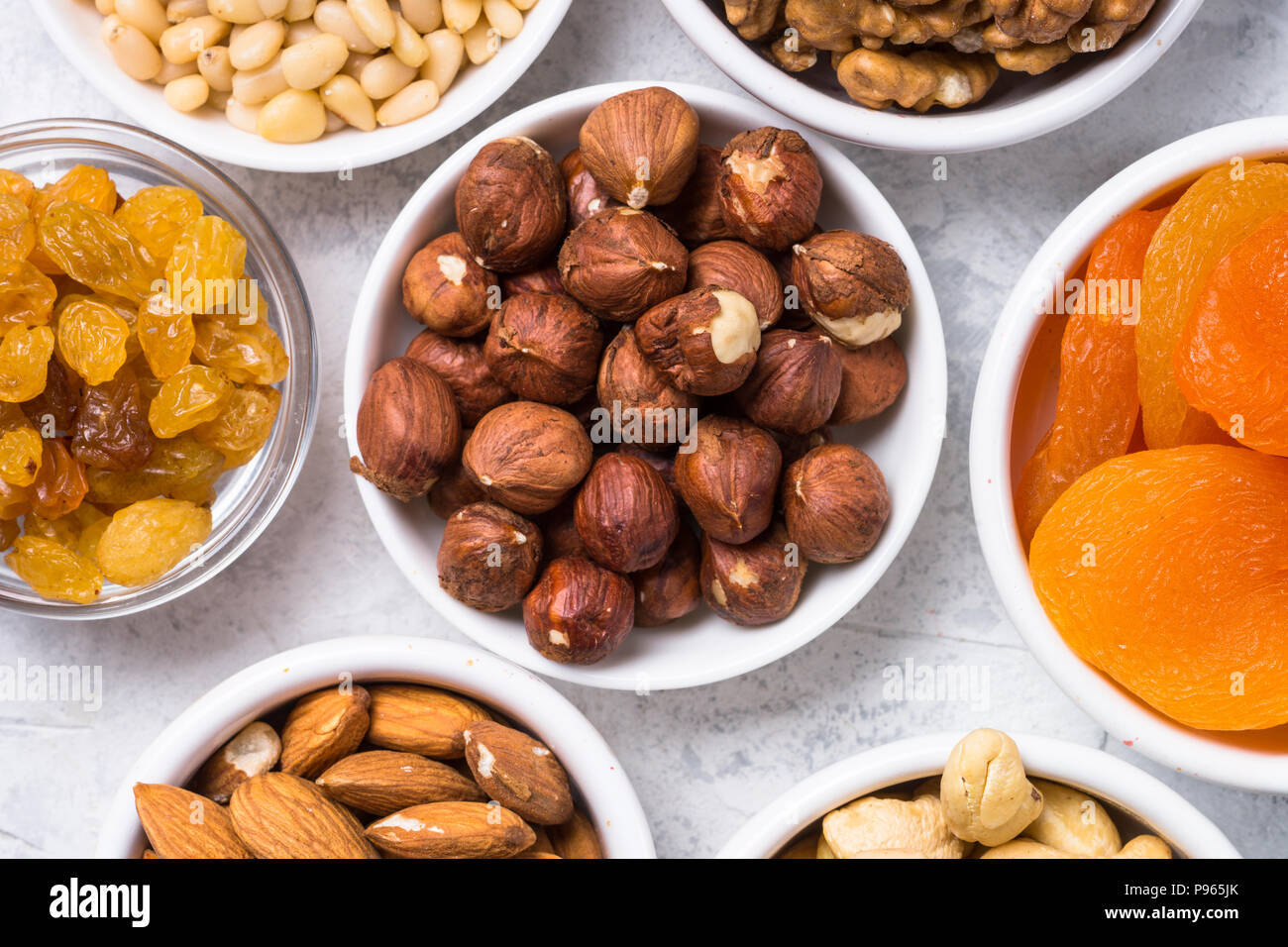 Assortment of nuts and dried fruits in bowls. Cashew, hazelnuts, walnuts, almonds, brazilian nuts, raisins, dried apricots and pine nuts. Top view wit Stock Photo