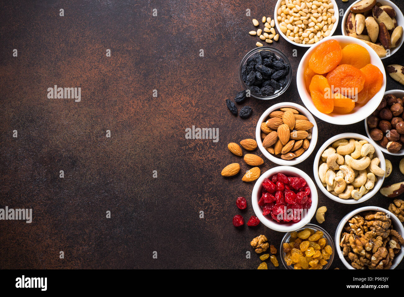Assortment of nuts and dried fruits in bowls. Cashew, hazelnuts, walnuts, almonds, brazilian nuts, raisins, dried apricots, cherry and pine nuts. Top  Stock Photo