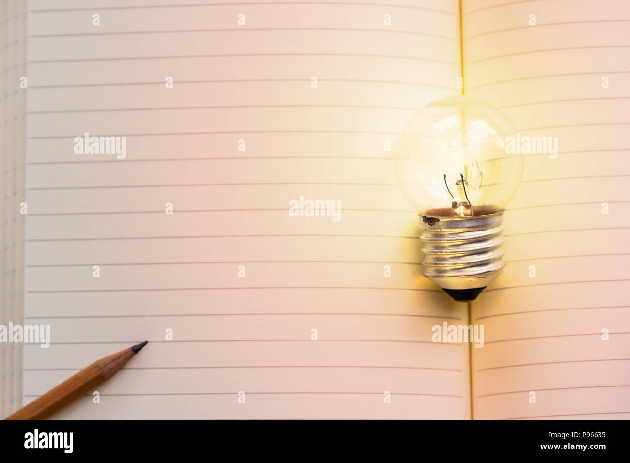 Concept idea. Growing light bulb on vintage book with pencil. Copy space for your text. conceptual great ideas are always available. Creative thinking Stock Photo