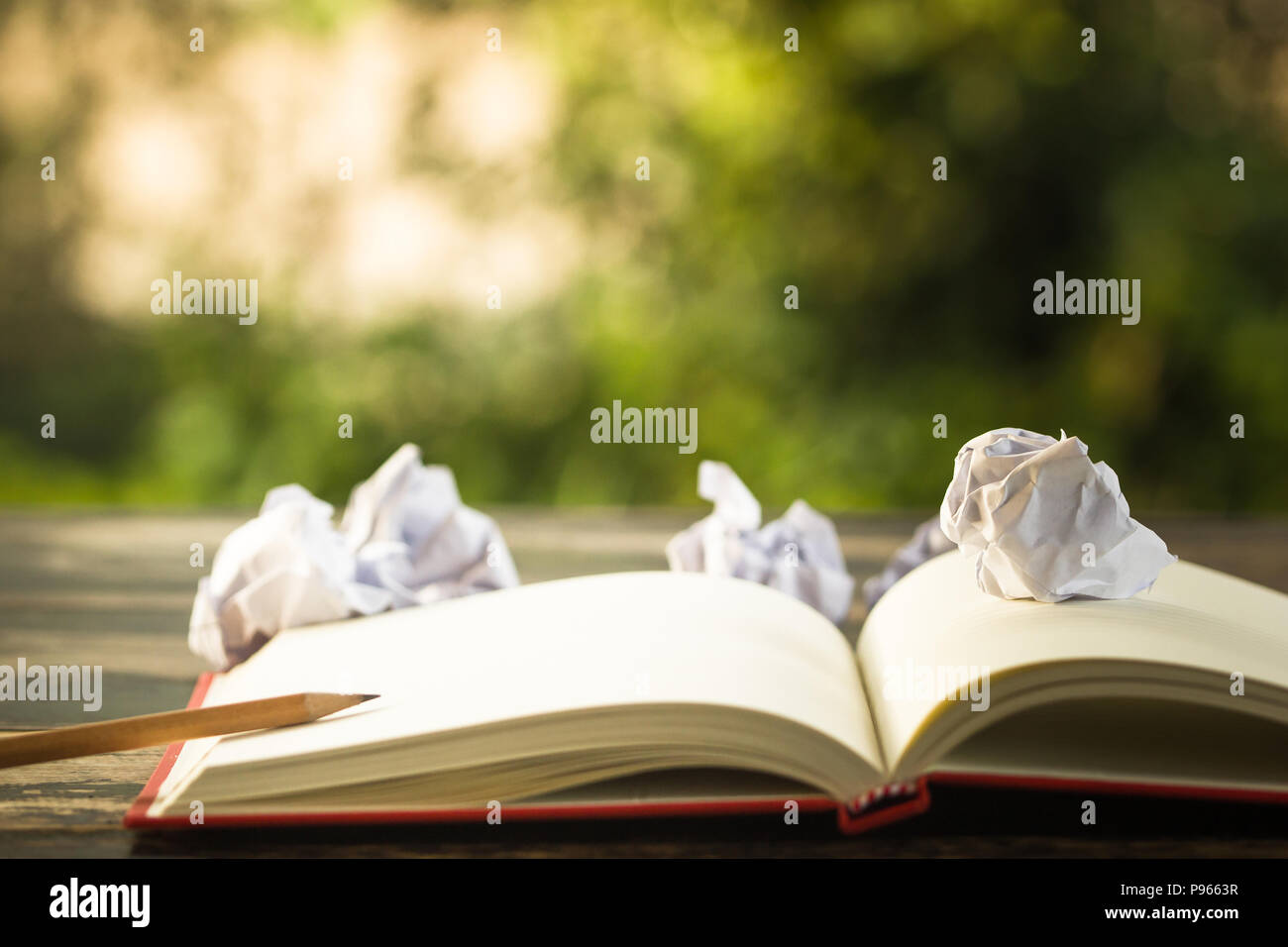 Concept idea. Open vintage book with crumpled papers ball and pencil. Copy space for your text. Conceptual great ideas are always available. Creative  Stock Photo