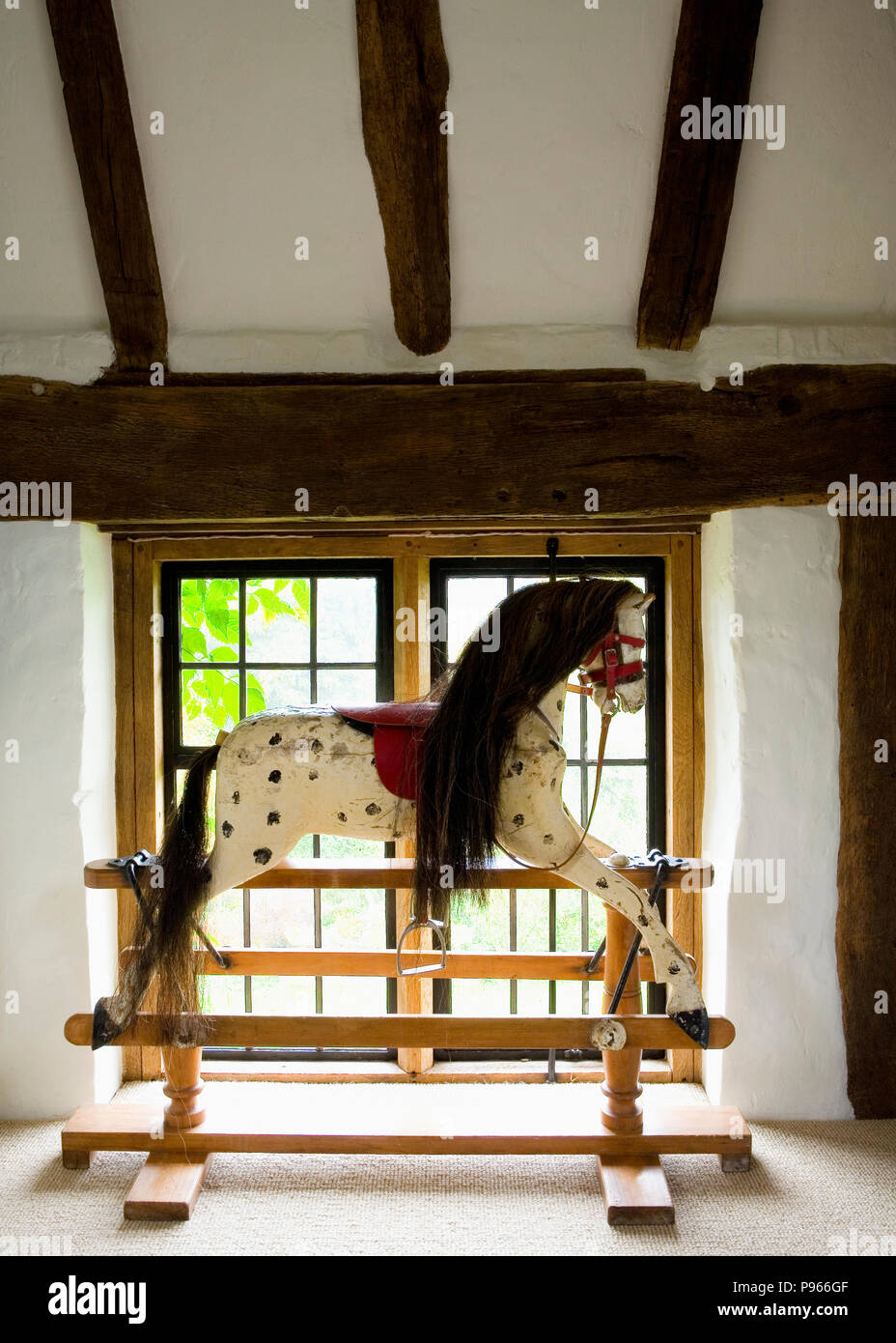 Antique swingstand rocking horse in front of landing window Stock