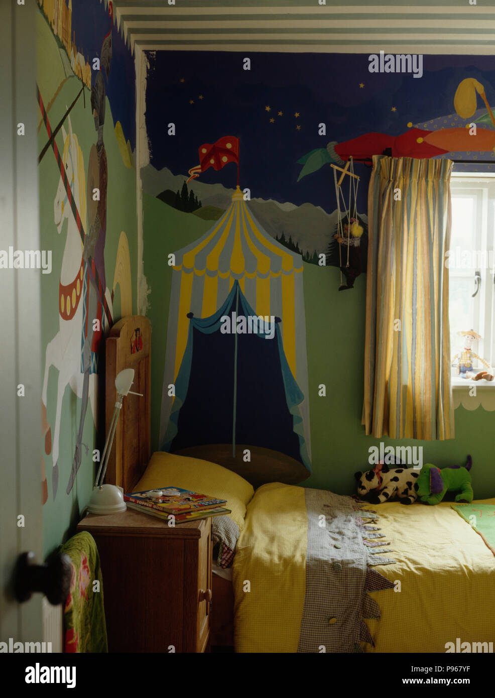 Paint effect mural on wall of child's bedroom with yellow bedlinen Stock Photo