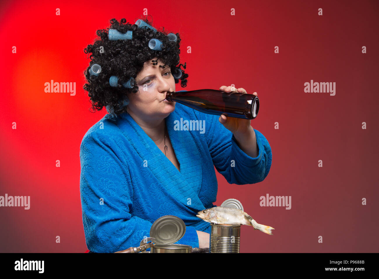 Lonely middleaged woman drinking beer and vodka from a glass tumbler