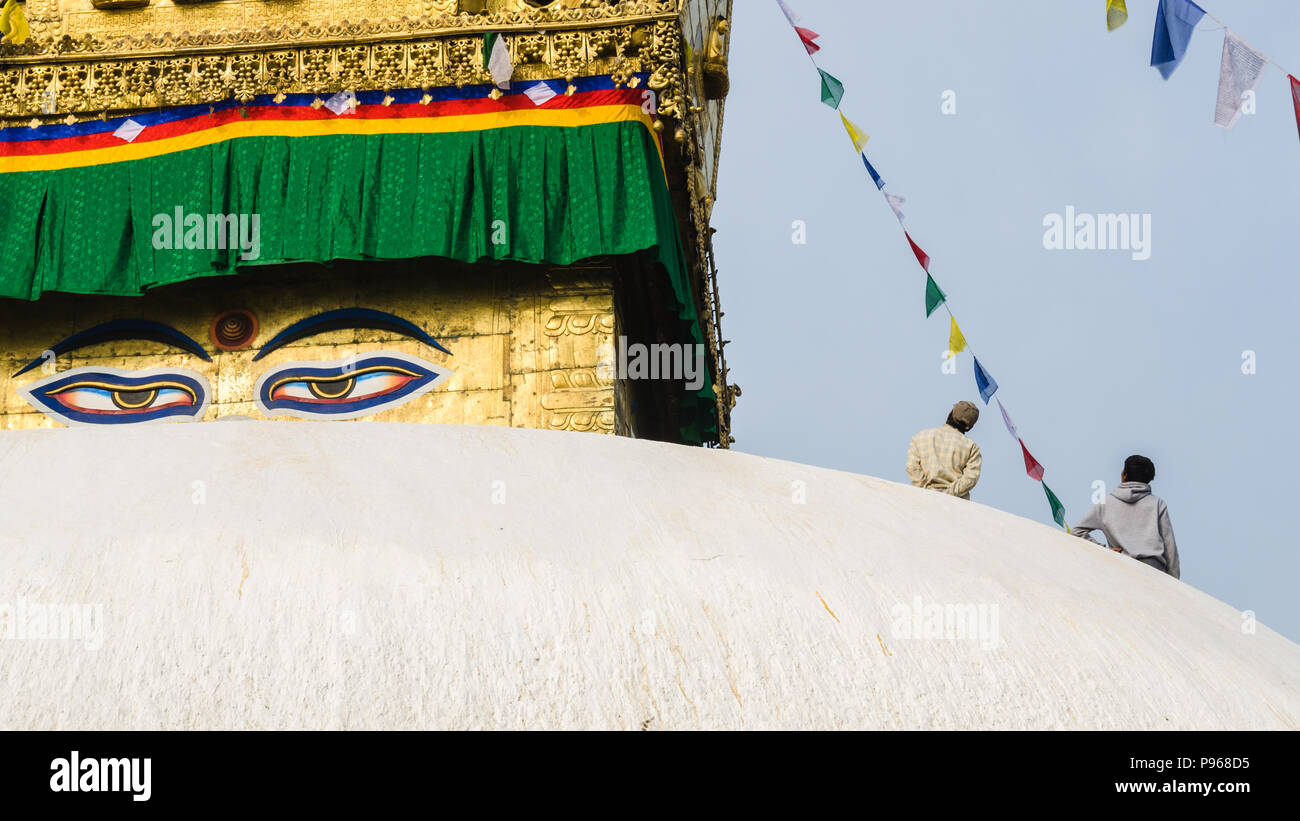 Two Nepalese installing Buddhist prayer flags at the top of Boudhanath stupa, Kathmandu, Nepal Stock Photo