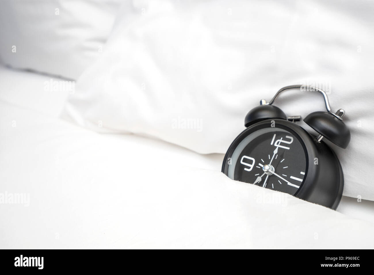 Analog alarm clock is on white bed, Time in the morning with a bright