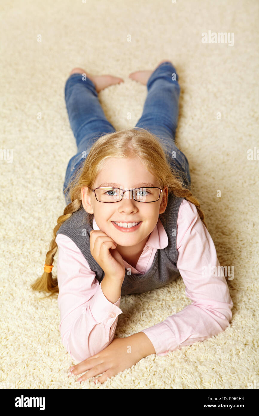 school age girl with glasses on a carpet Stock Photo