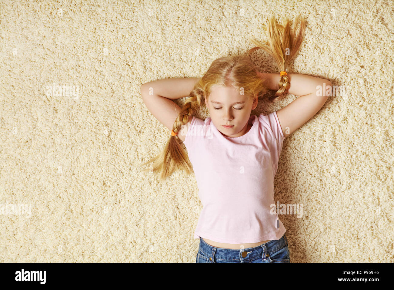 school age girl lying on a carpet Stock Photo