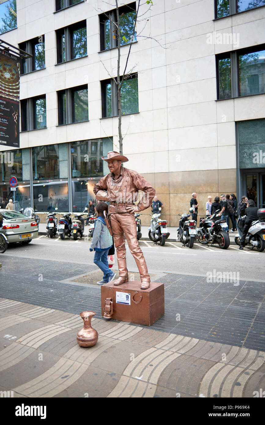 Barcelona, Spain. April 19, 2017: Man simulating a sculpture of a cowboy from an American West movie with clothes painted bronze color completely moti Stock Photo