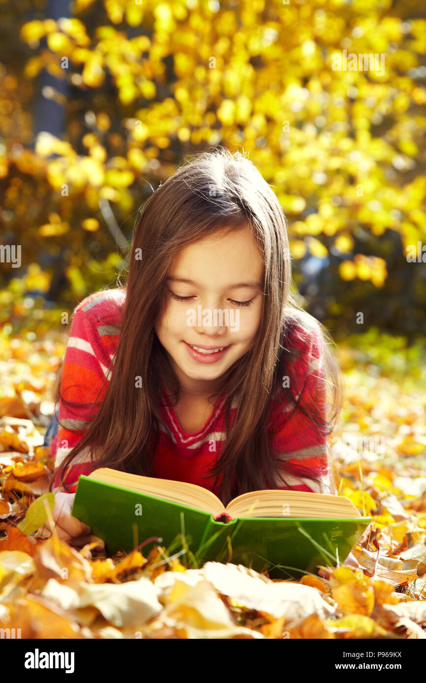 girl lying on fallen leaves and reading a book Stock Photo