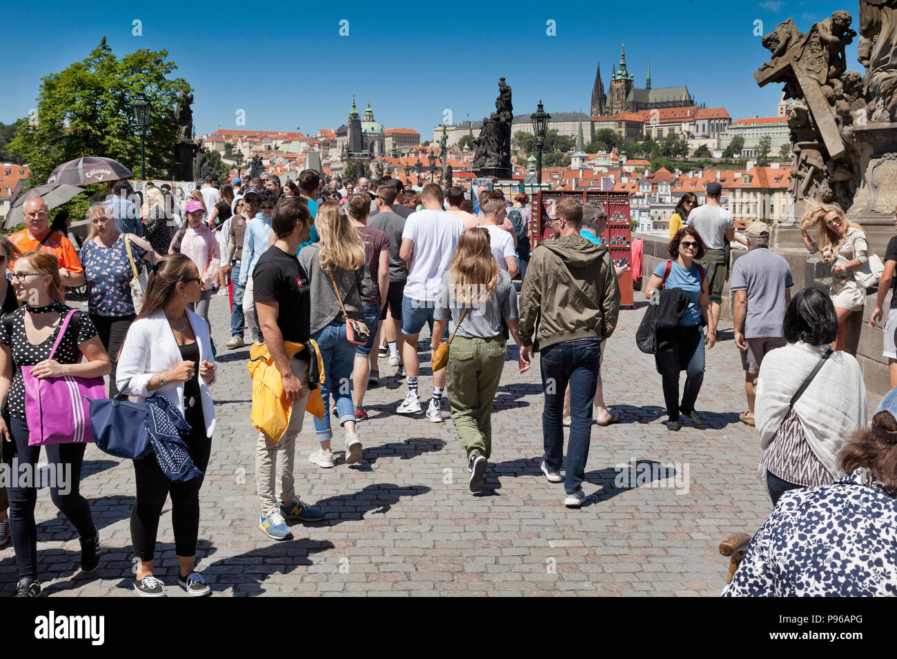 Tourists on Charles Bridge, Prague, Czech Republic, bright sun, blue sky. Stock Photo