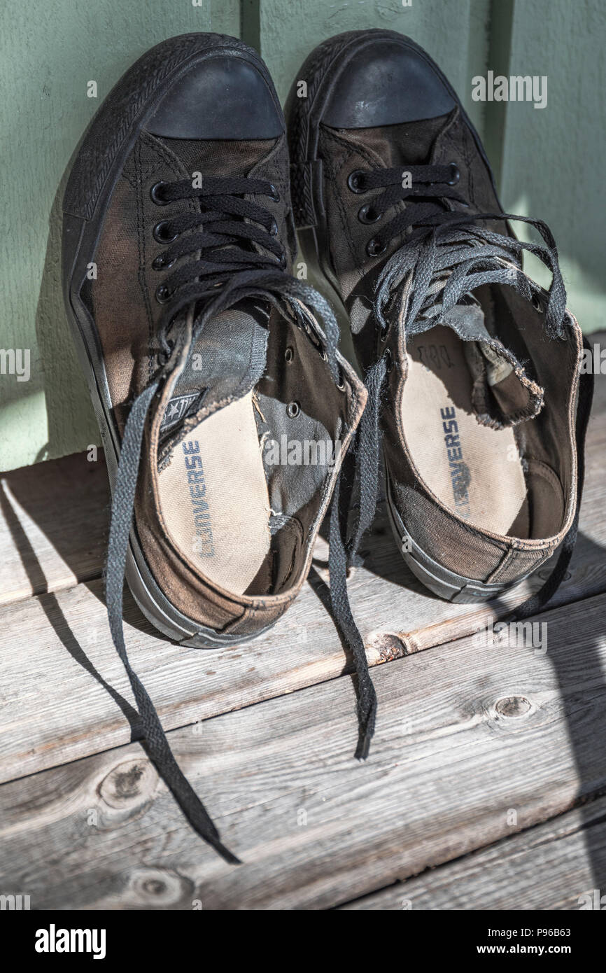 Close up view of black classic worn out Converse All Star shoes leaning up against wall Stock Photo