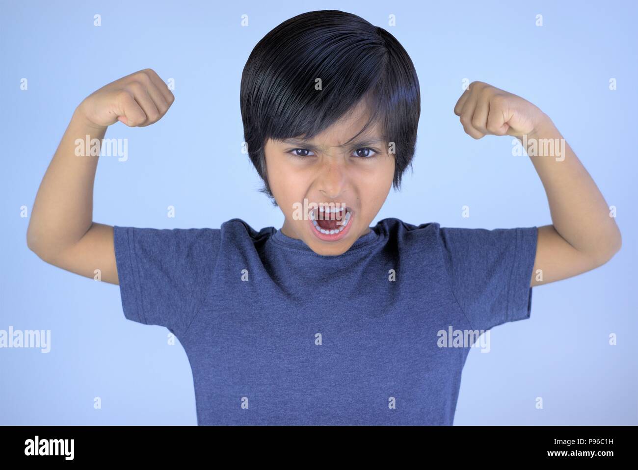 Angry kid screaming or yelling with raised arms and closed fists Stock Photo