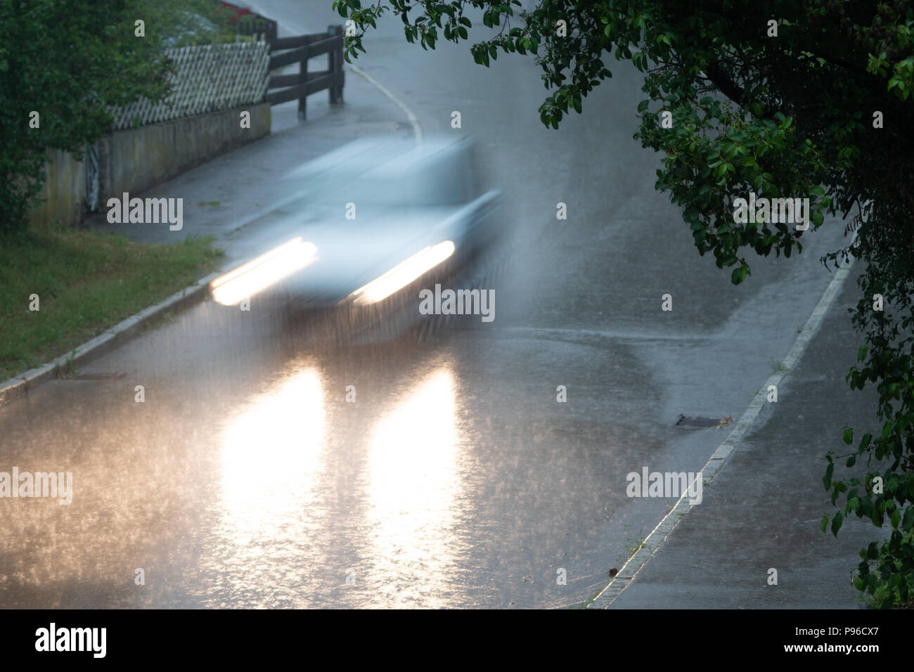 Car driving the street down in the rain Stock Photo Alamy