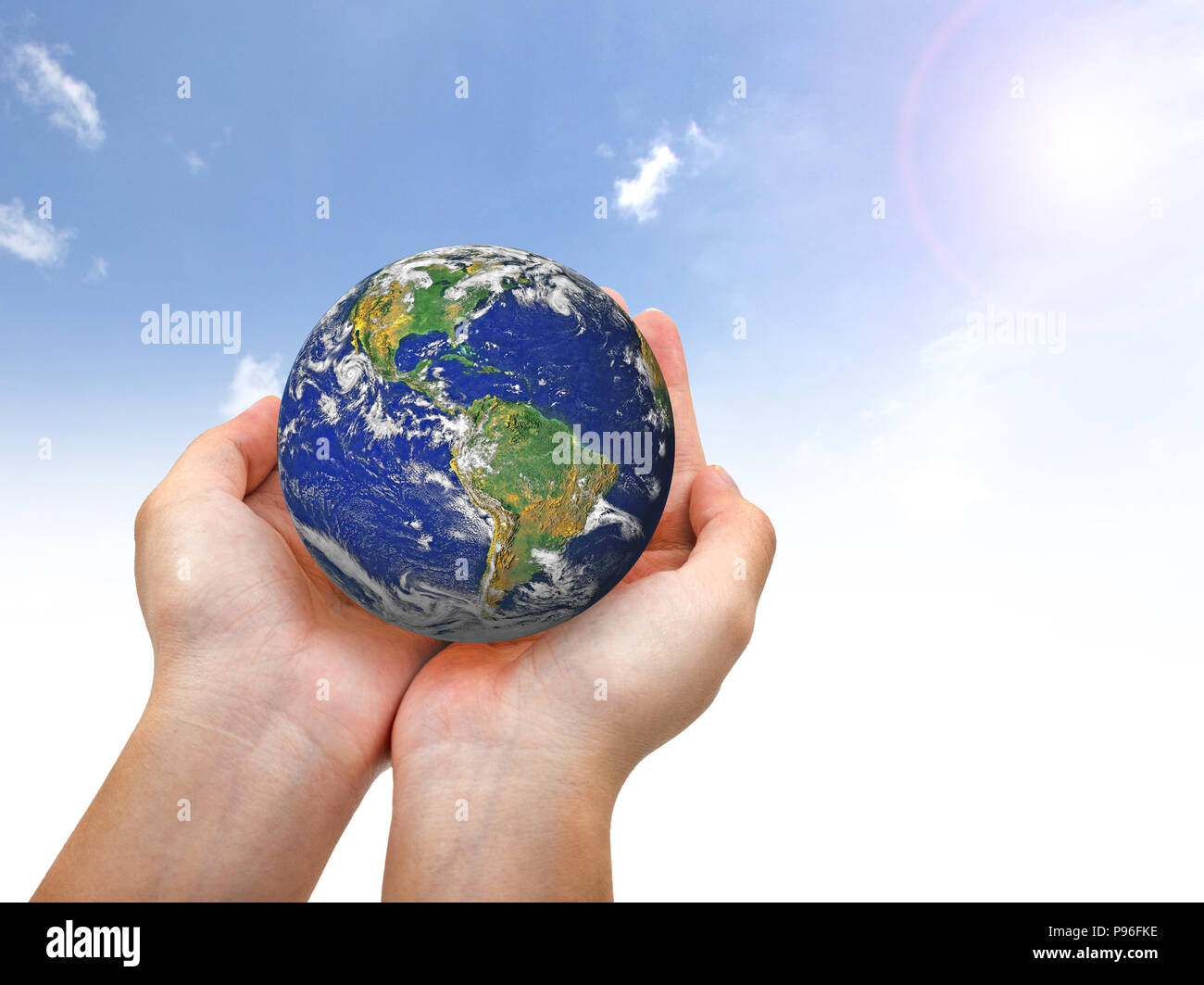 Earth planet in female hand and blue sky - Elements of this image furnished by NASA Stock Photo