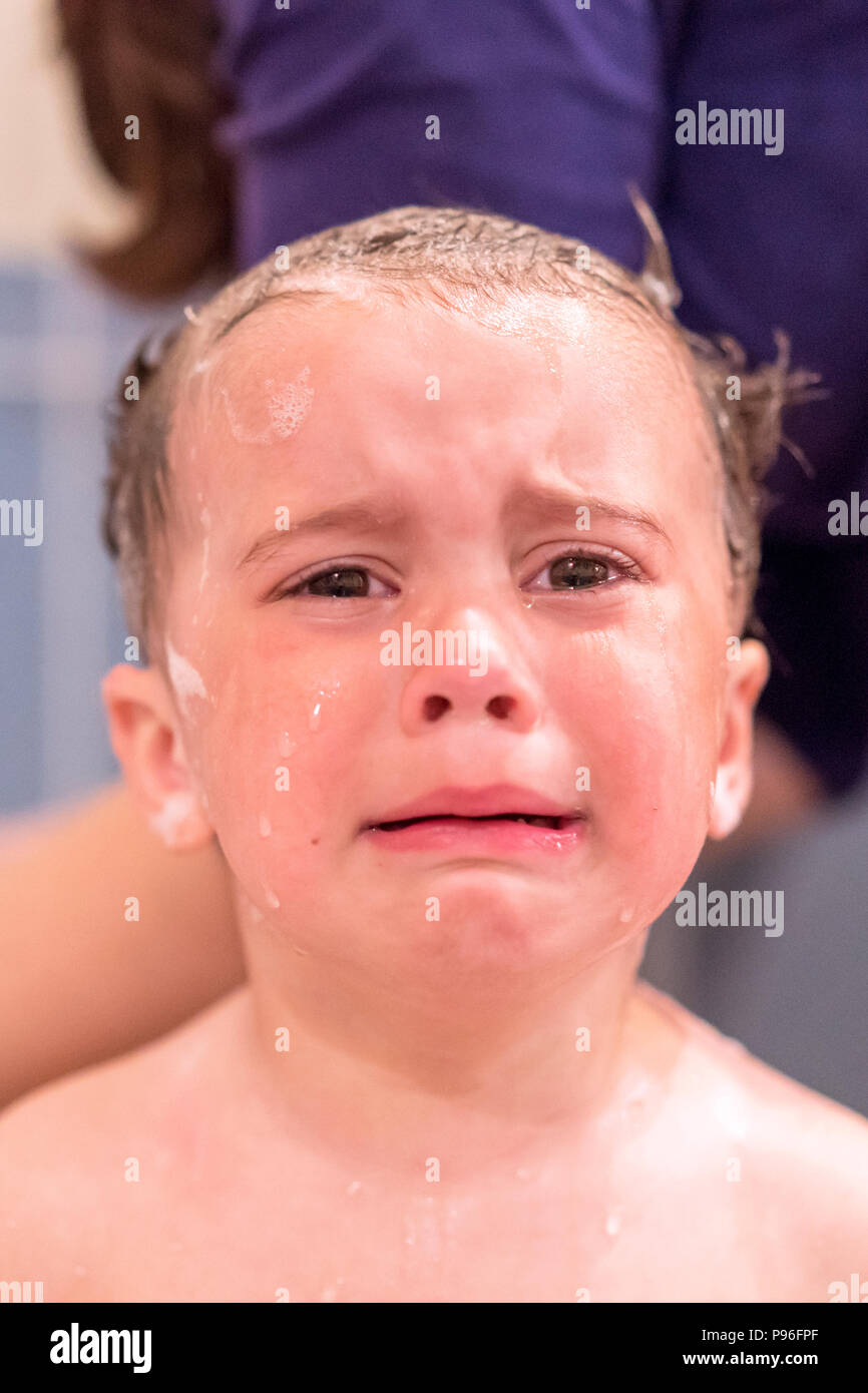 Crying baby by in a bathtub. Infant kid sreaming while taking a bath