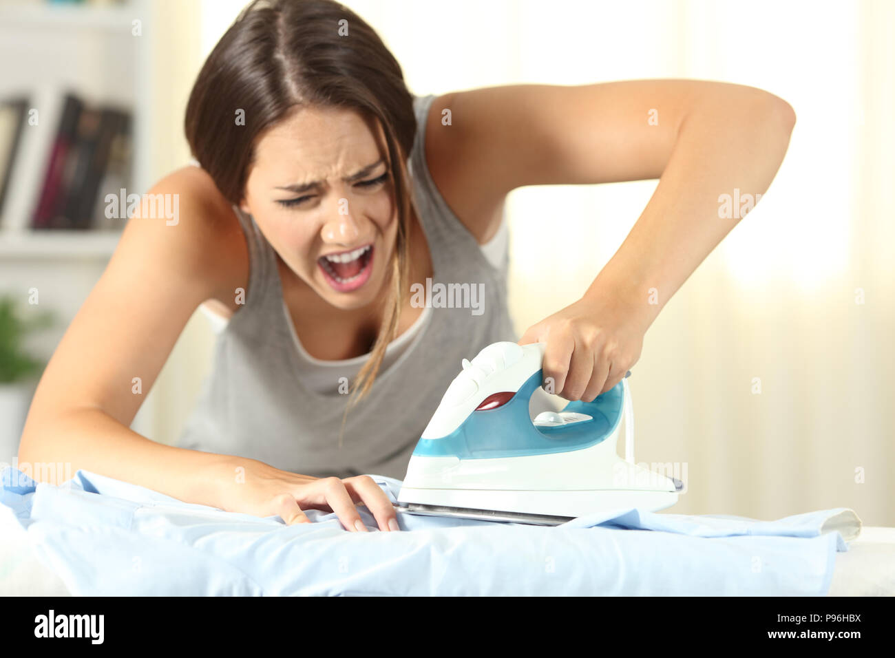 Woman burning a finger with a smoothing iron at home Stock Photo