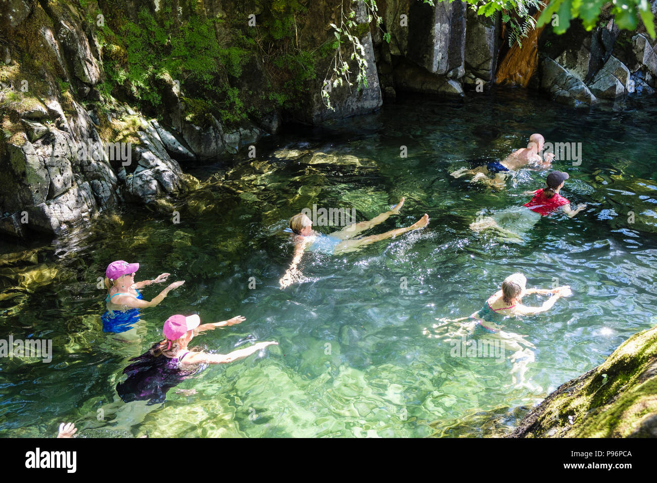 People wild swimming in a rocky pool in Langstrath Beck on a hot summer ...