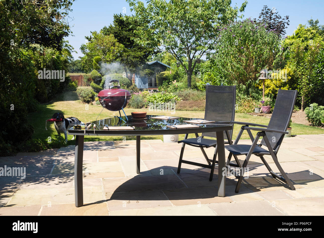 BBQ smoking on a picnic table in a domestic back garden in summer. Kent, England, UK, Britain Stock Photo