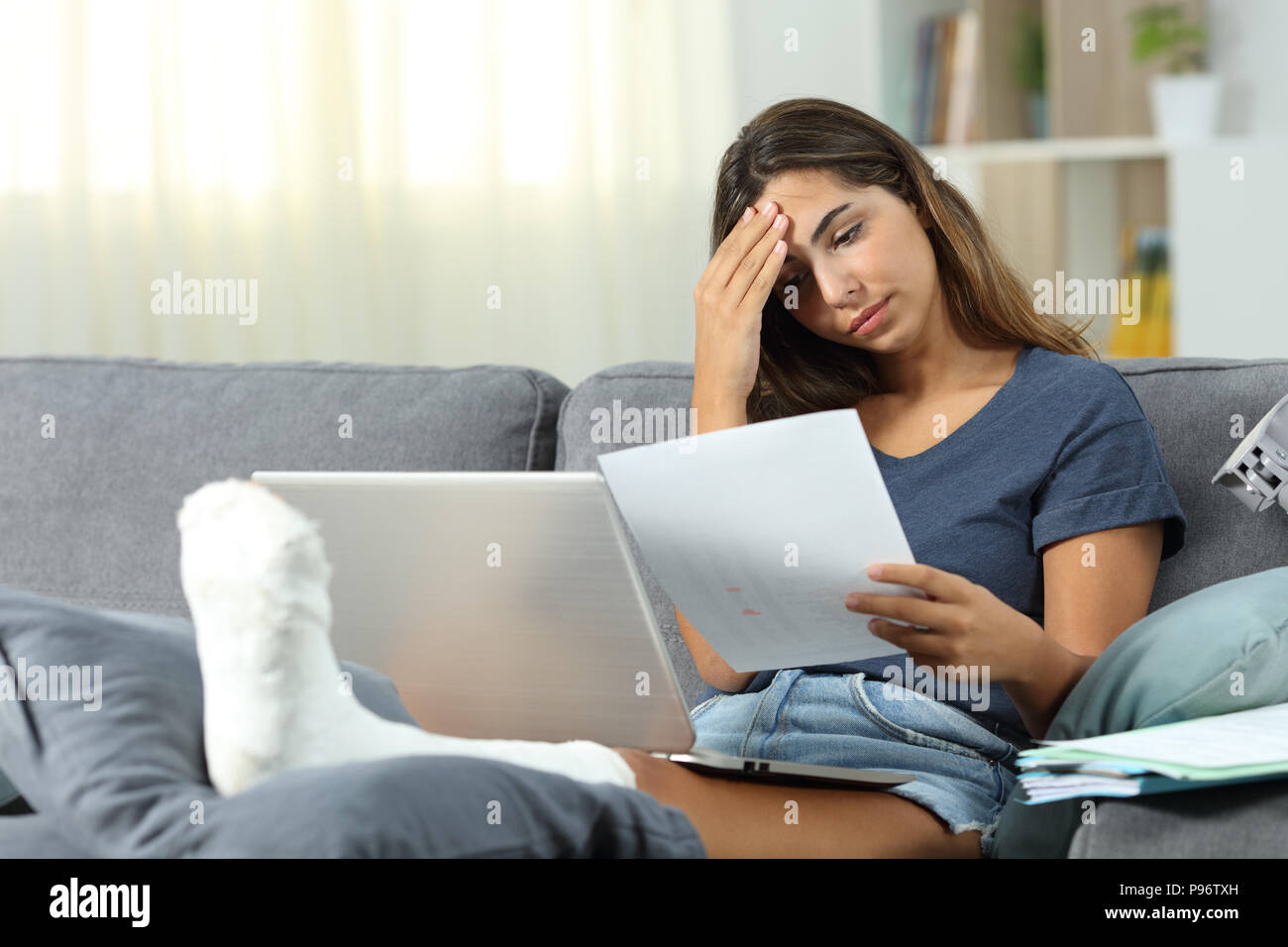 Worried disabled self employed working sitting on a couch in the living room at home Stock Photo