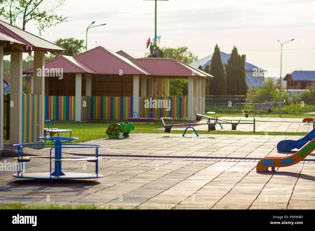 Beautiful new modern playground in kindergarten with soft pavement, bright new multicolored alcoves, swings, slides, benches, roundabout and sandbox.  Stock Photo