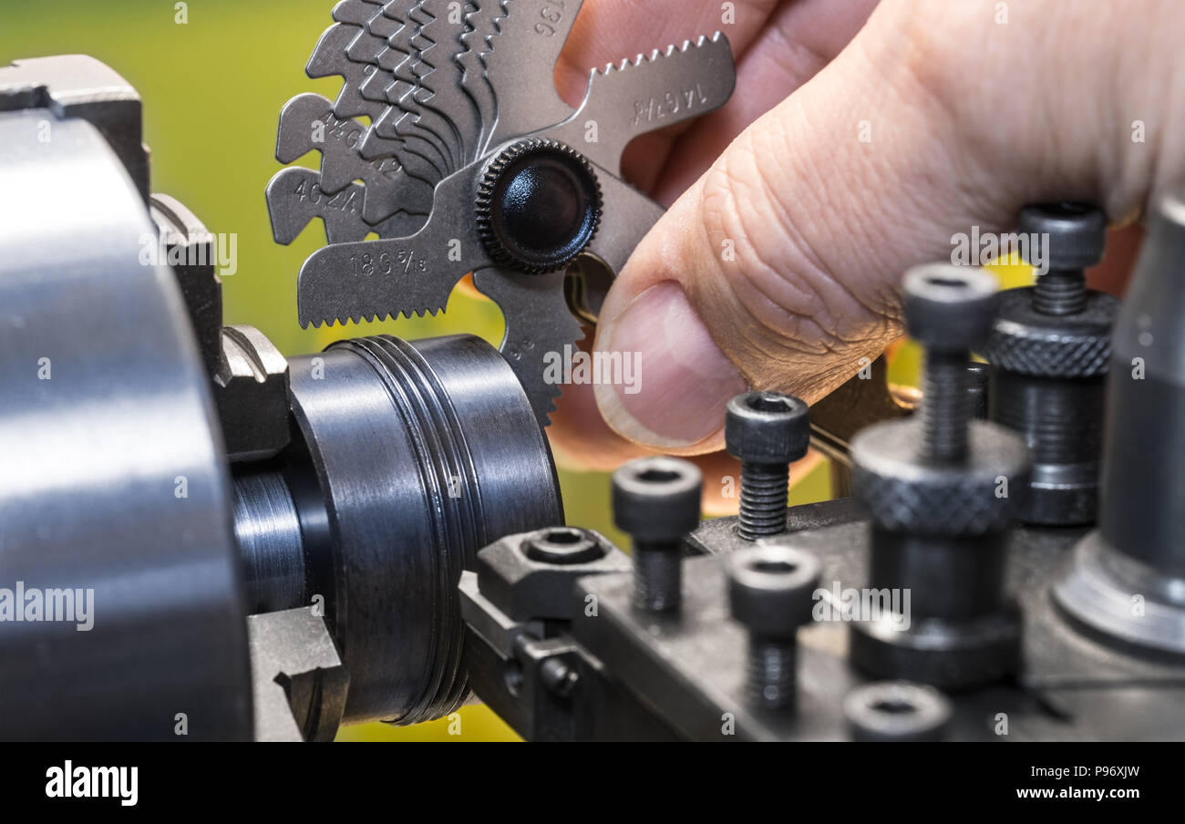 Close-up of measurement by thread pitch gauge. Detail of a machinist's hand with the set of threaded gauges. Threading by a steel tool bit on a lathe. Stock Photo