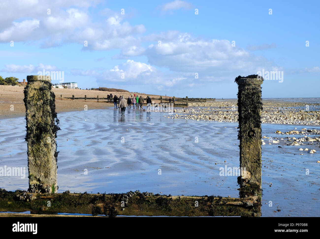 East Preston, UK. Group of people walking along the beach at low tide on a winter's afternoon. Stock Photo