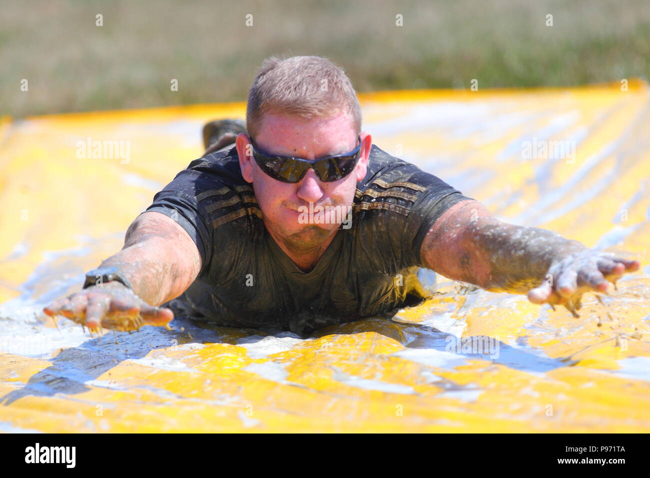 A man takes his tuen on a mud slide during a Young Mudder event in Leeds which participants can choose to do a 2.5k or 5k muddy obstacle course. Stock Photo