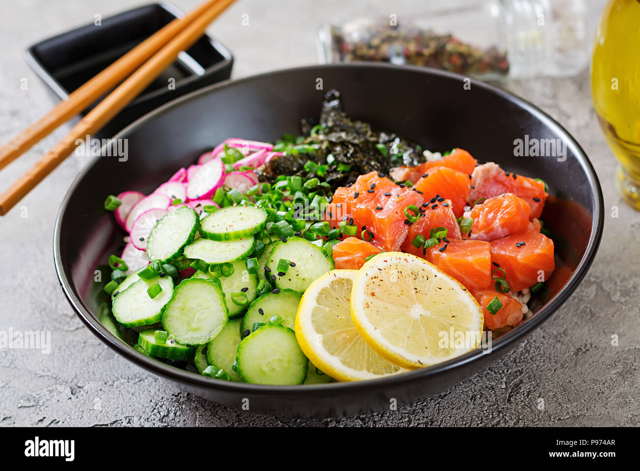 Hawaiian salmon fish poke bowl with rice, radish,cucumber, tomato, sesame seeds and seaweeds. Buddha bowl. Diet food Stock Photo