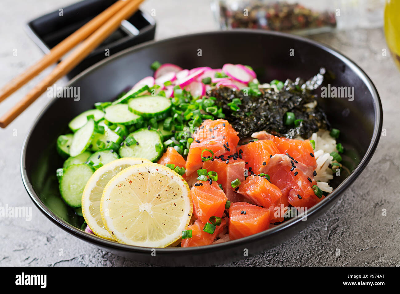 Hawaiian salmon fish poke bowl with rice, radish,cucumber, tomato, sesame seeds and seaweeds. Buddha bowl. Diet food Stock Photo