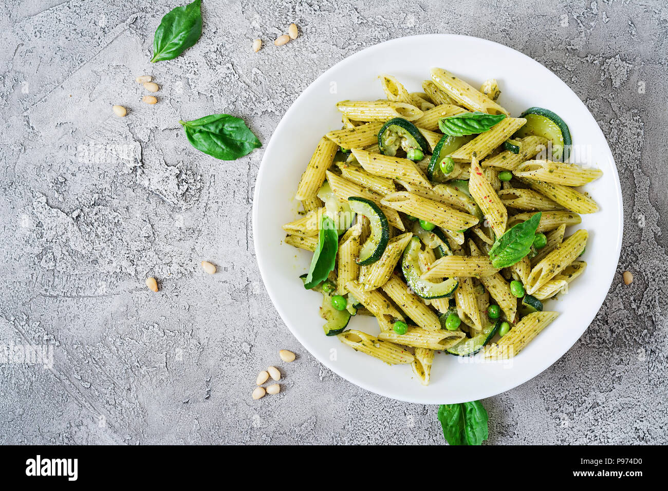 Penne pasta with pesto sauce, zucchini, green peas and basil. Italian
