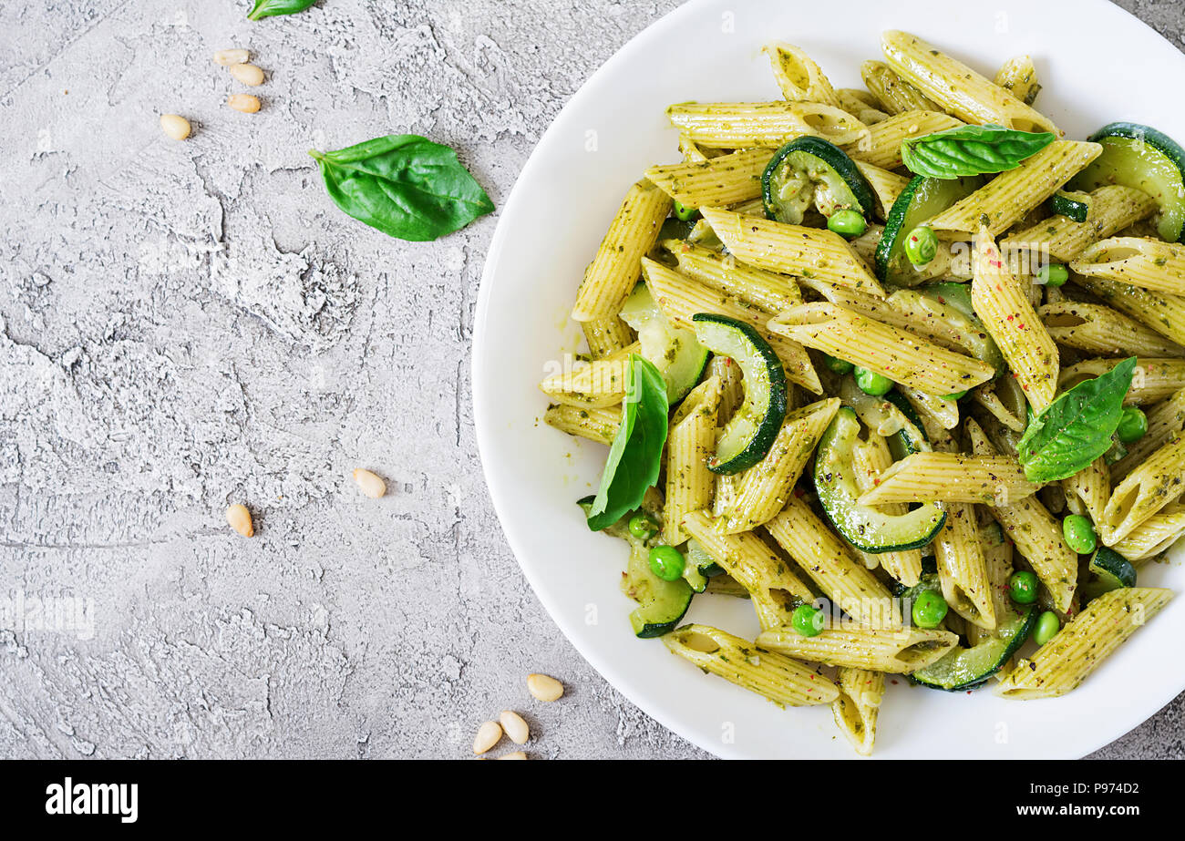 Penne pasta with pesto sauce, zucchini, green peas and basil. Italian