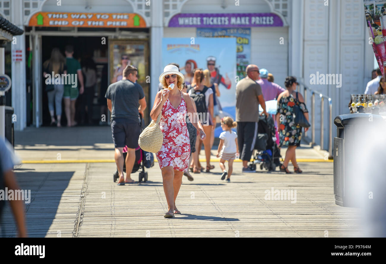Brighton UK 15th July 2018 - Time to enjoy an ice cream on Brighton Palace Pier in glorious hot sunshine as the temperatures soar into the low 30s in some parts of the South East of Britain today Credit: Simon Dack/Alamy Live News Stock Photo