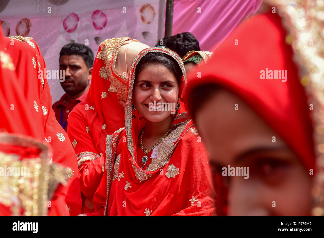 Srinagar, India. 15th July 2018. Kashmiri Muslim brides reacts during mass marriage event in Srinagar, Indian controlled Kashmir on Sunday. Mass wedding of 105 Muslim couples held in Srinagar organised by social welfare organisation primarily to help the economically backward families who cannot afford the high costs of the ceremony, dowry and expensive gifts, that still prevails in many communities of India. Credit: SOPA Images Limited/Alamy Live News Stock Photo