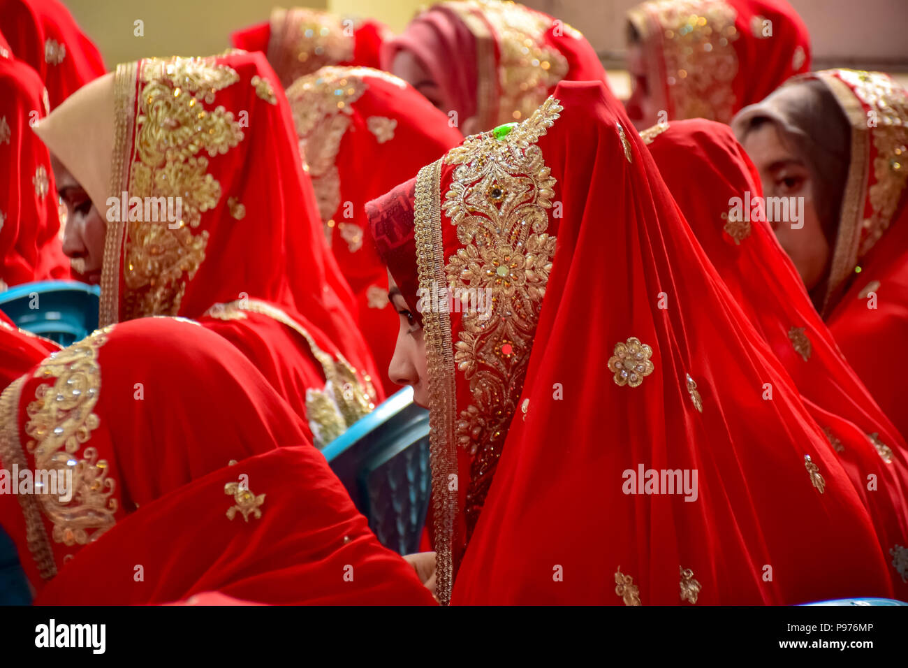 Srinagar, India. 15th July 2018. Kashmiri Muslim brides sit for a mass marriage event in Srinagar, Indian controlled Kashmir on Sunday. Mass wedding of 105 Muslim couples held in Srinagar organised by social welfare organisation primarily to help the economically backward families who cannot afford the high costs of the ceremony, dowry and expensive gifts, that still prevails in many communities of India. Credit: SOPA Images Limited/Alamy Live News Stock Photo
