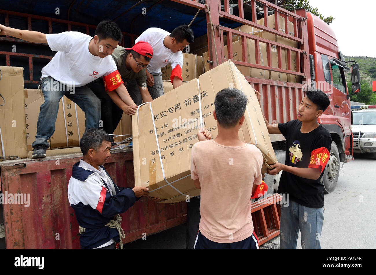 Zhouqu, China's Gansu Province. 15th July, 2018. Villagers unload relief supplies for flood victims in Nanyu Town of Zhouqu County, northwest China's Gansu Province, July 15, 2018. Emergency relief supplies have been sent to severely flooded areas in Zhouqu County and rescue work has been carried out here. Heavy rainstorms triggered a landslide Thursday in Zhouqu County, but no casualties have been reported. Credit: Fan Peishen/Xinhua/Alamy Live News Stock Photo