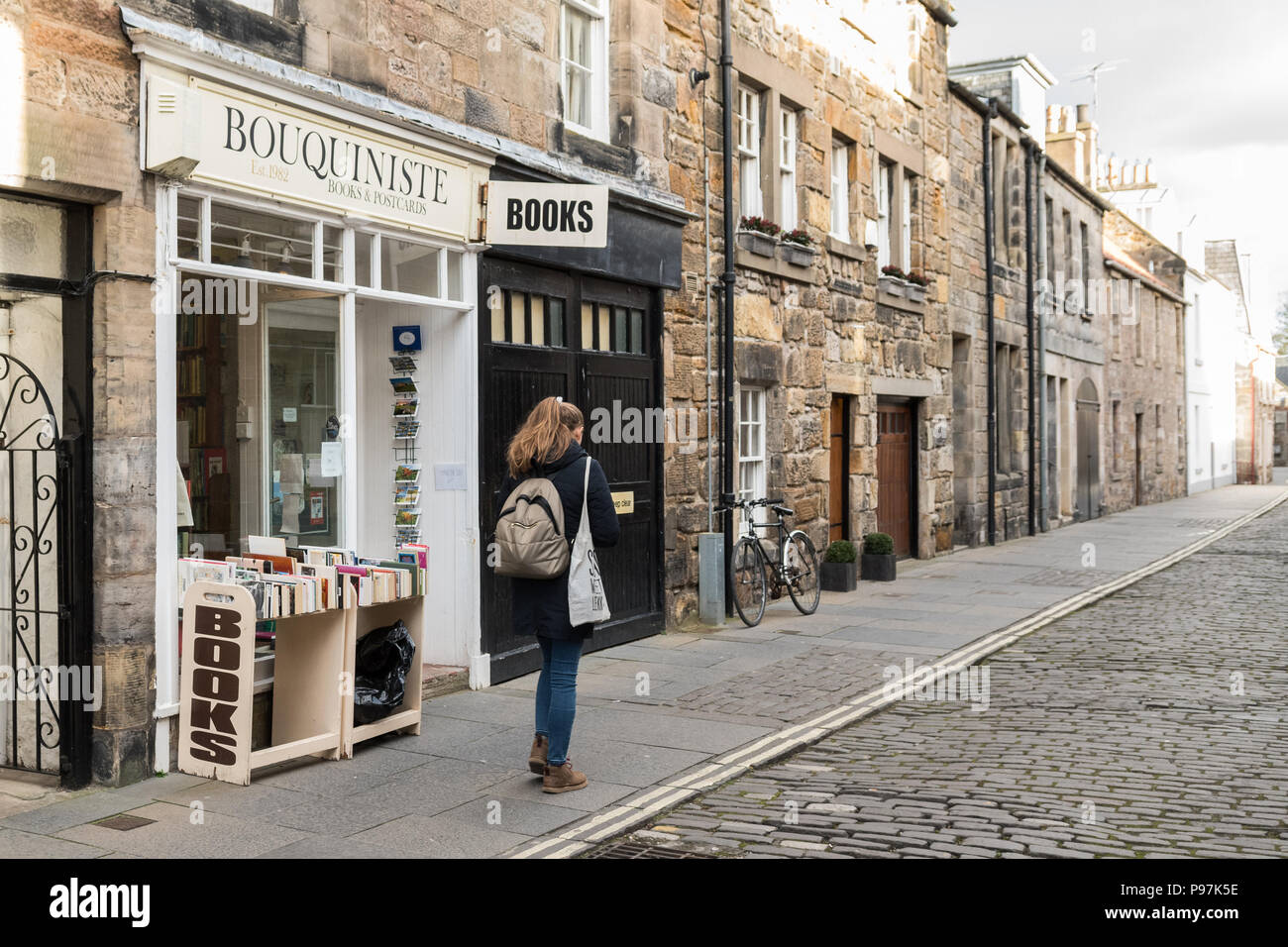 Female student walking by used bookshop, Bouquiniste, Market Street, St Andrews, Scotland, UK Stock Photo