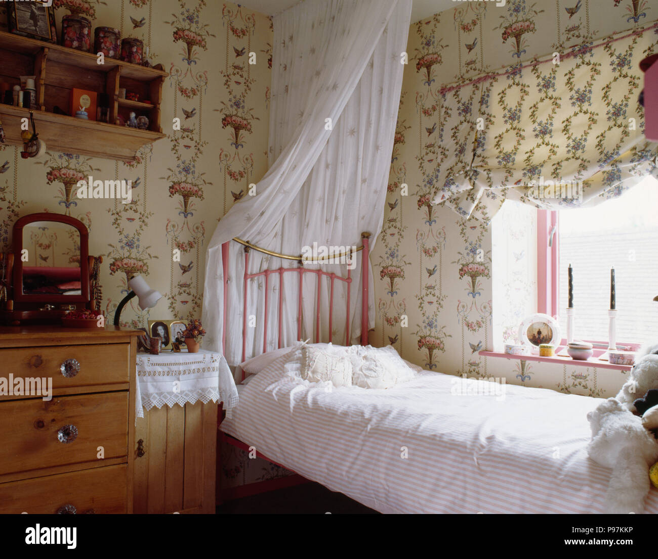 Patterned wallpaper and blind in teenager girls bedroom with white drapes  on pink single brass bed Stock Photo - Alamy