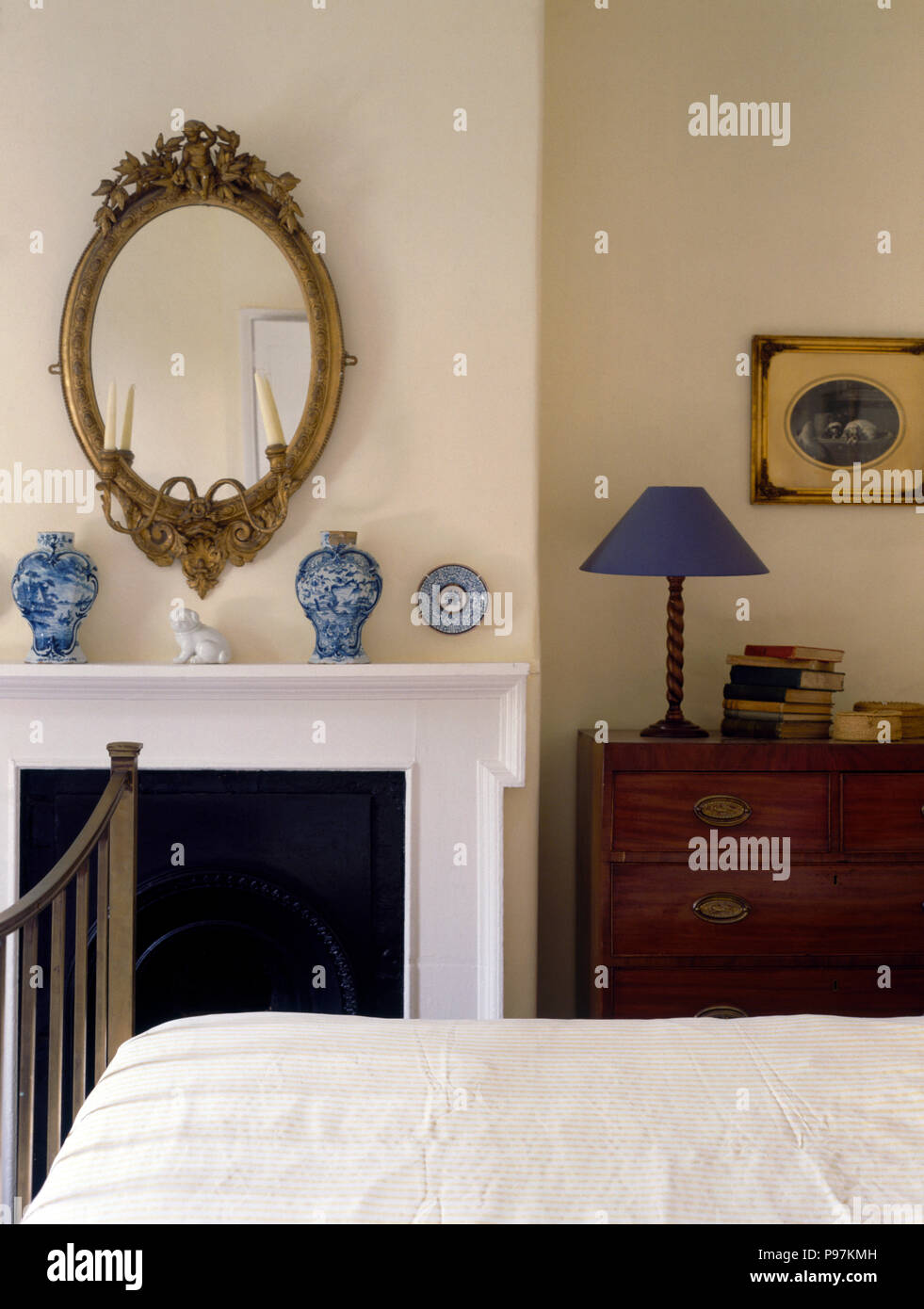 Oval antique mirror above fireplace with blue vases in an economy style