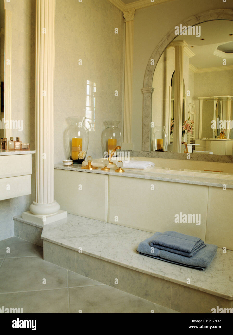 Classical pillar beside raised bath in cream traditional bathroom Stock Photo