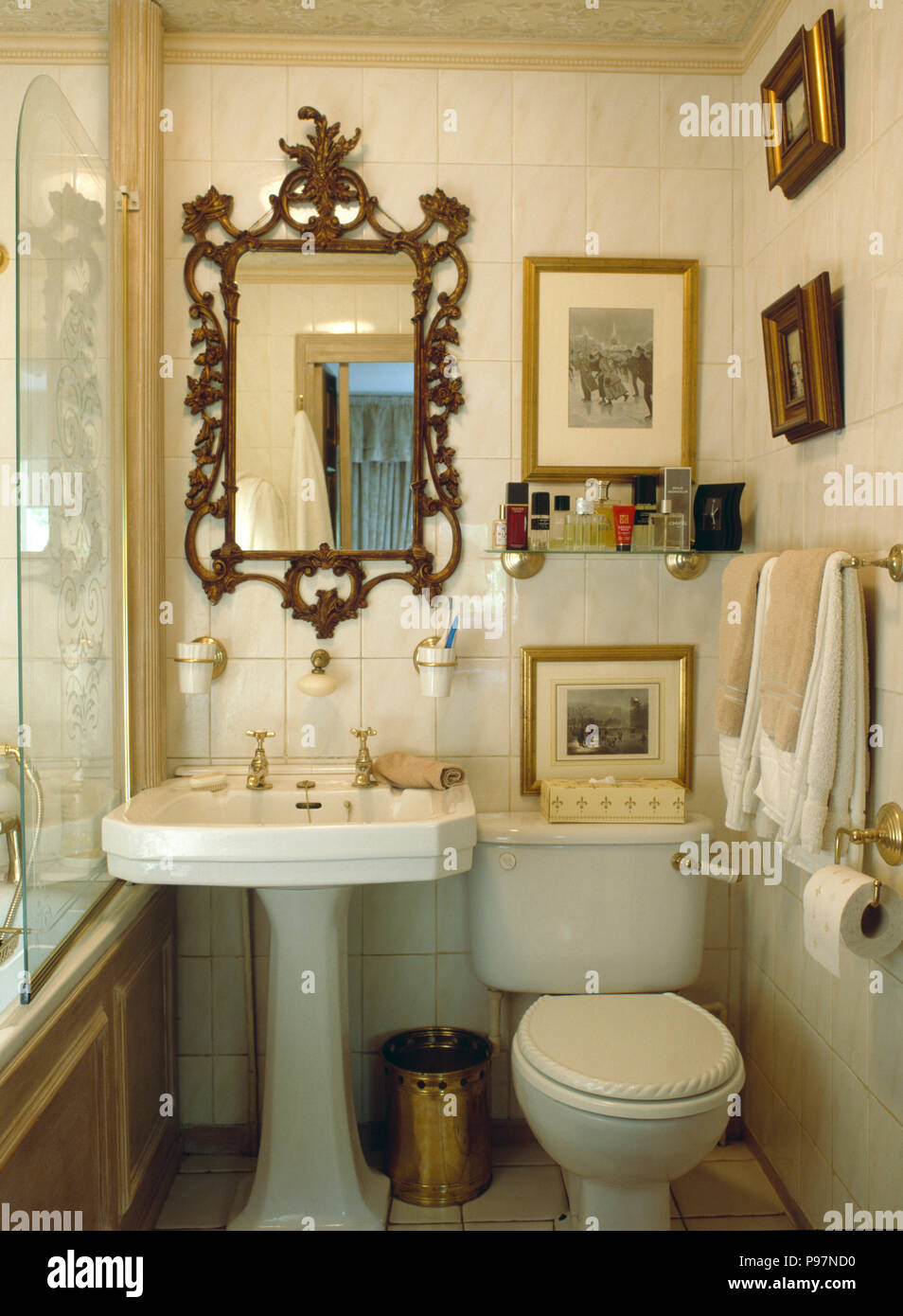 Antique mirror above white pedestal basin and toilet in narrow bathroom pictures on the walls Stock Photo