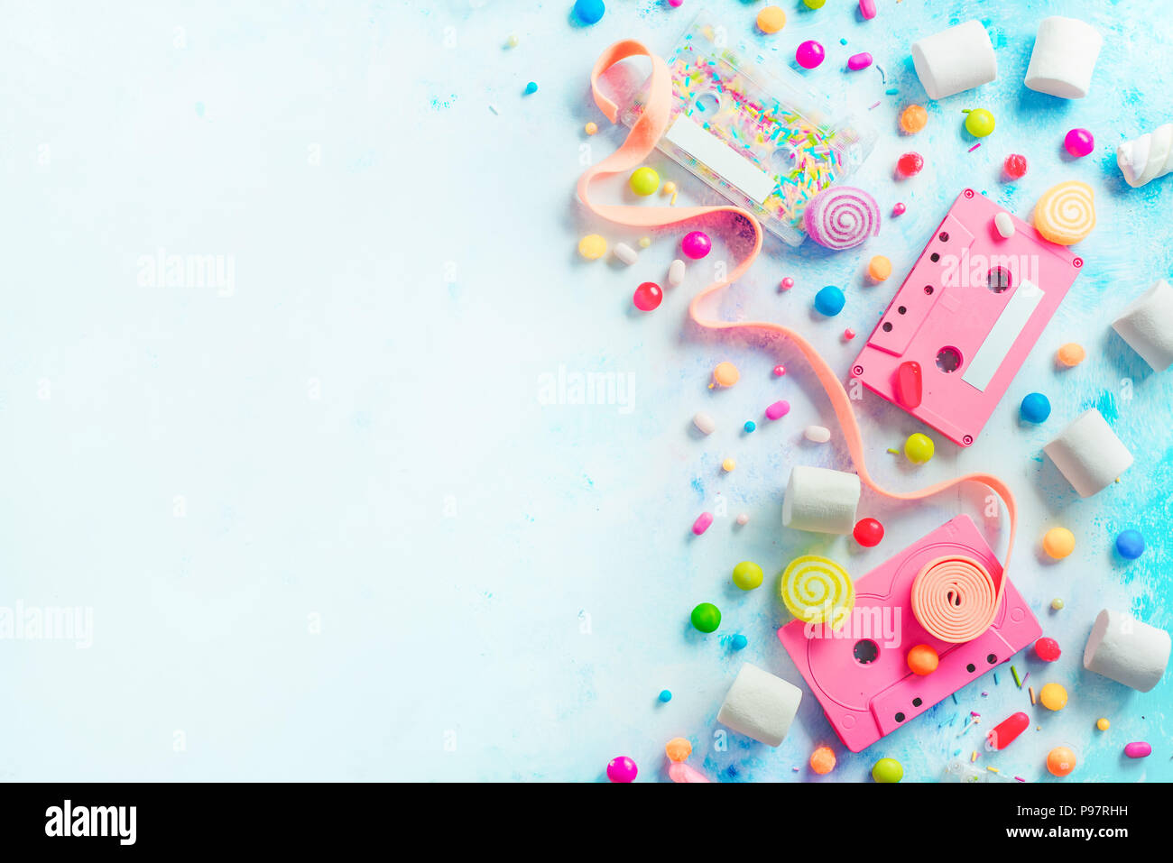 Pink cassette tapes in a sweet sounds concept. Candies, sprinkles and marmalades on a light background with copy space. Pastel color flat lay header Stock Photo