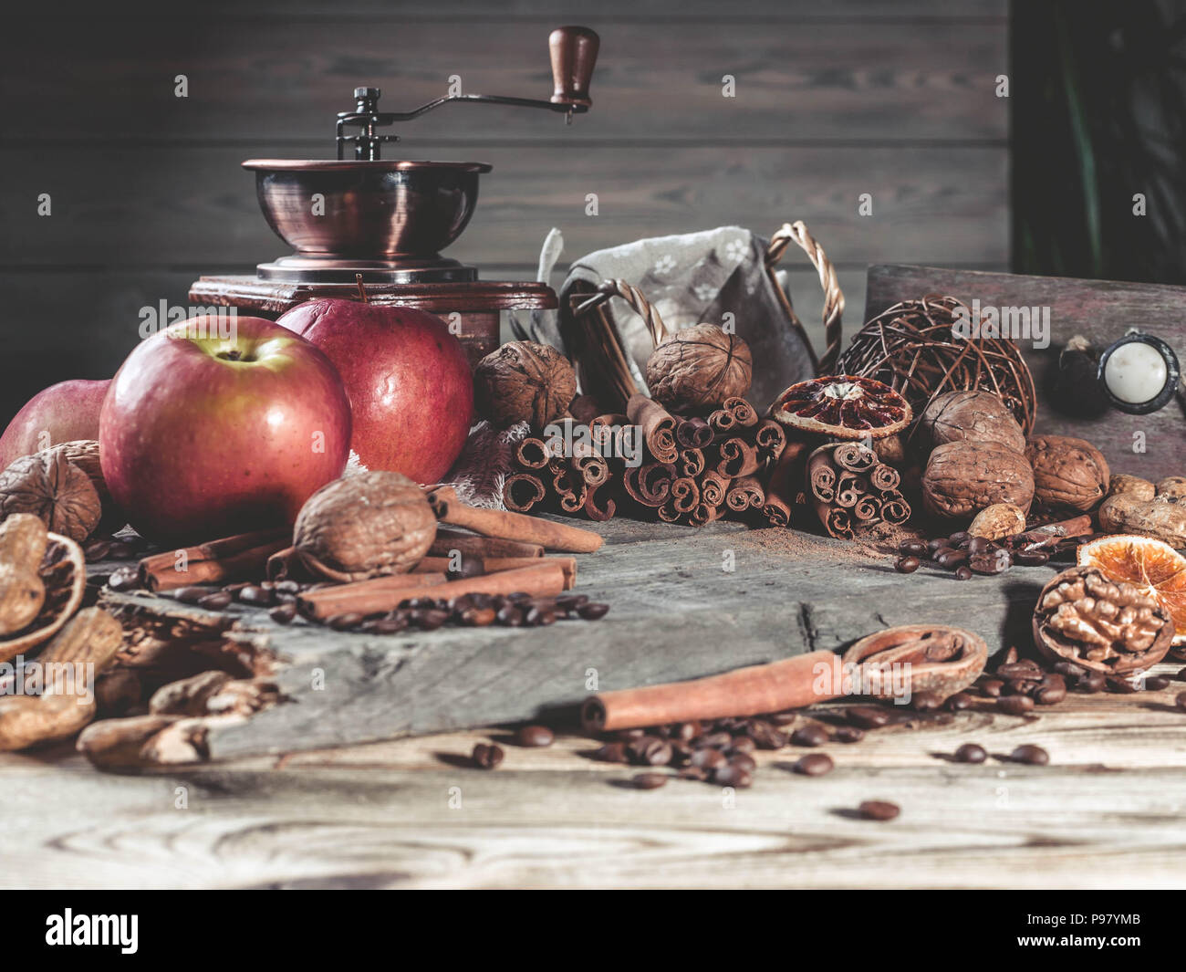 Nuts, cinnamon sticks, coffee beans, coffee grinder and ripe apples on